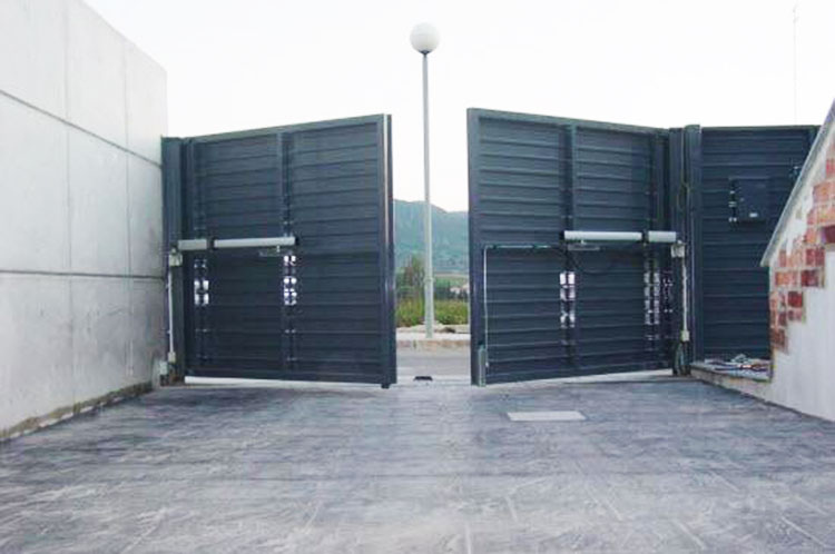 Puerta batiente automática de doble hoja instalada en acceso residencial